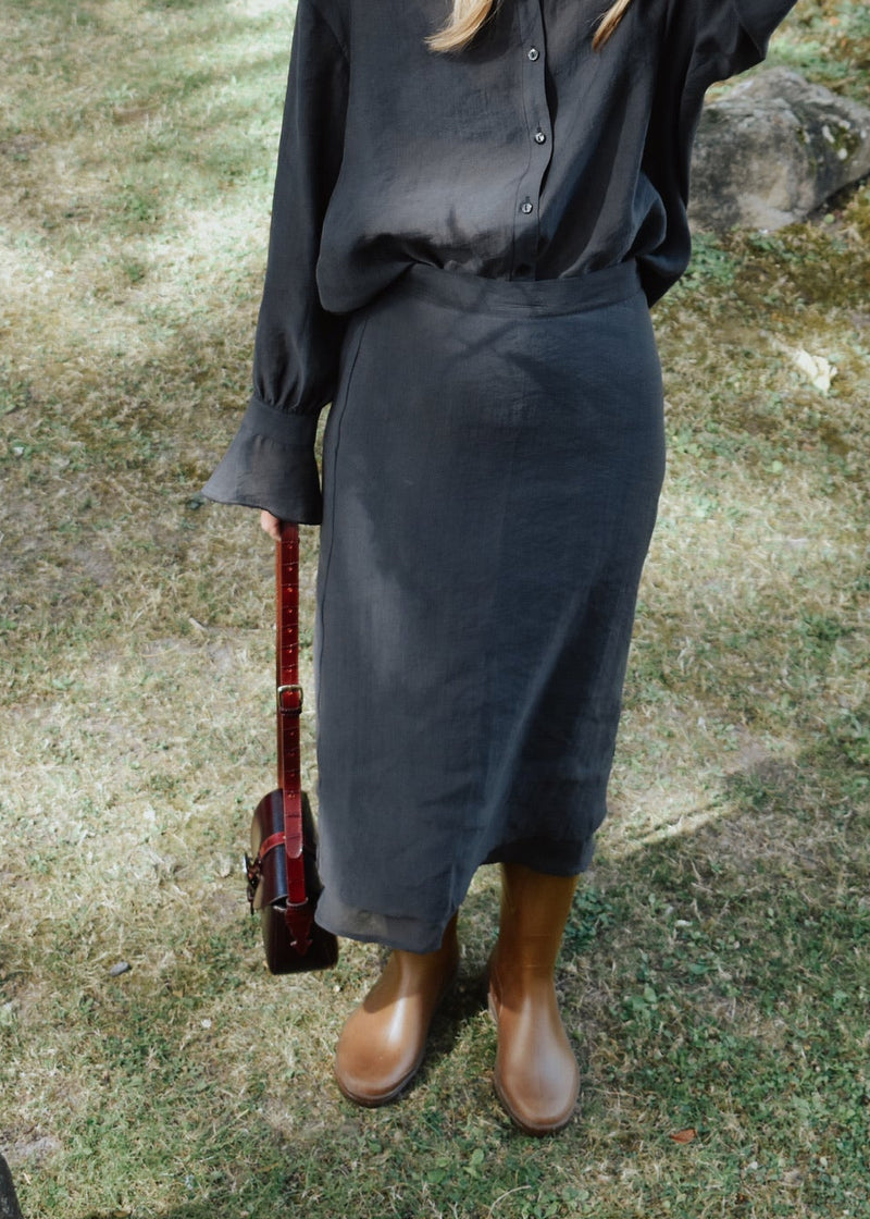 Jupe Ninon anthracite portée avec chemise assortie, look femme en extérieur